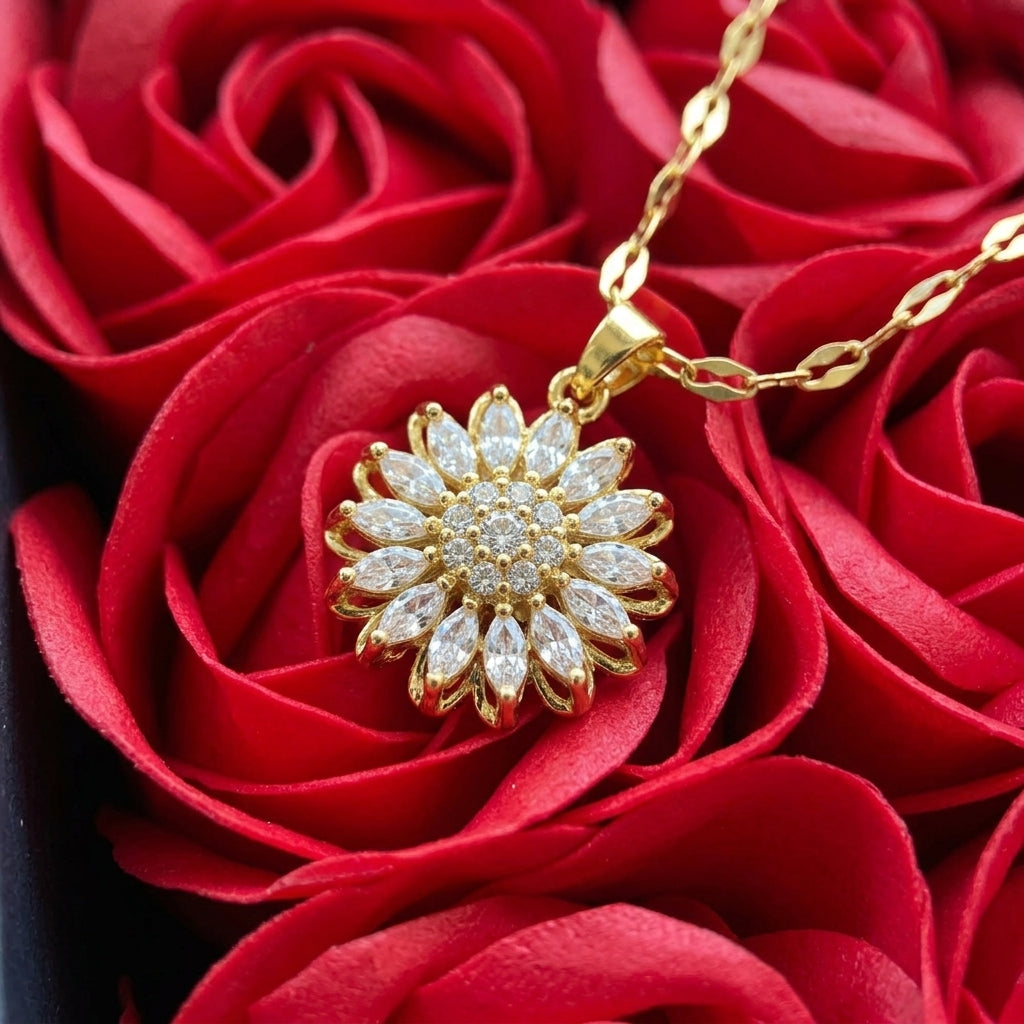 Detalle del dije girasol dorado con circonias blancas apoyado sobre las rosas rojas